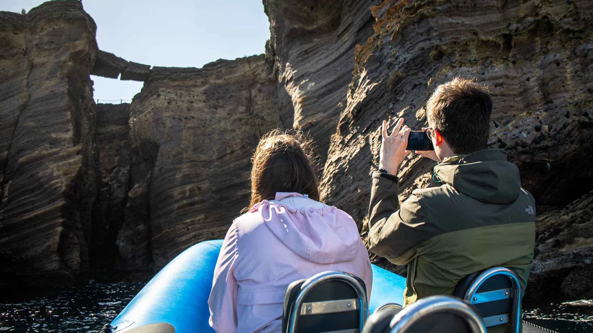 Boat passengers photographing the sheer cliffs of the Ilheu de Vila Franca do Campo