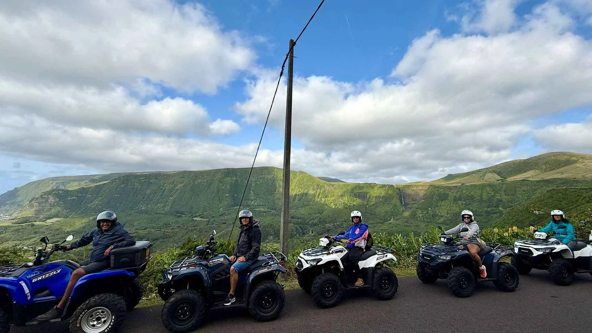 A line of quad bikes and riders on a country road in the green hills of Flores island